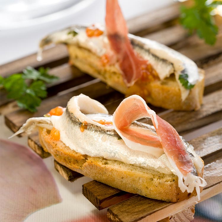 Canapé de boquerones en vinagre, jamón y tomate