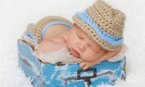 Bebé con un sombrero dormido en una caja