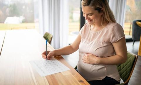 Mujer embarazada con un calendario tachando los días hasta el parto