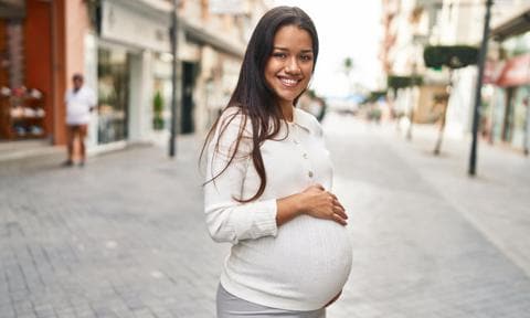 Mujer embarazada sonriendo en la calle