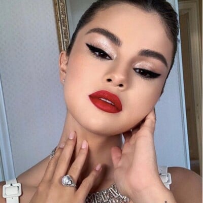 Selena Gómez con cabello recogido, cat eye y labios rojos