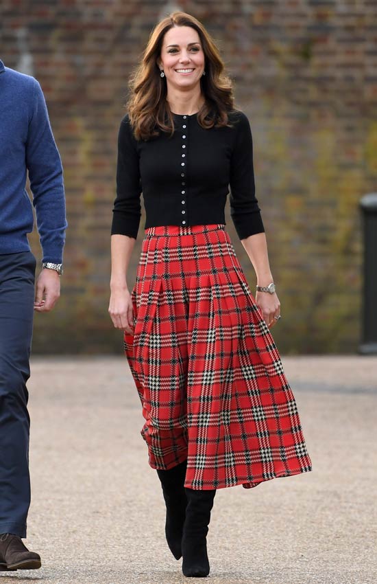 Kate Middleton con falda roja de cuadros y chaqueta de punto negra