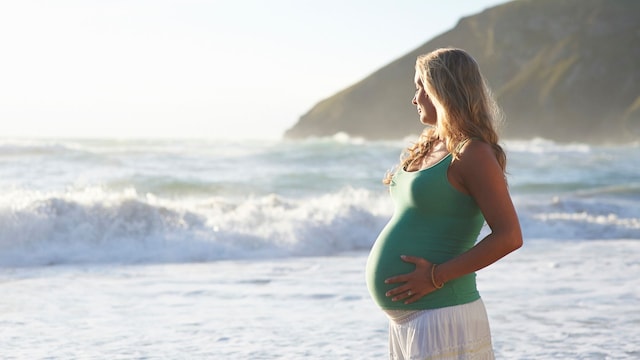 Una mujer en la playa se lleva las manos a la barriga