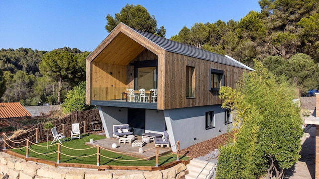Casa modular en dos plantas con la pared superior de madera, jardín y porche con muebles de exterior de palets