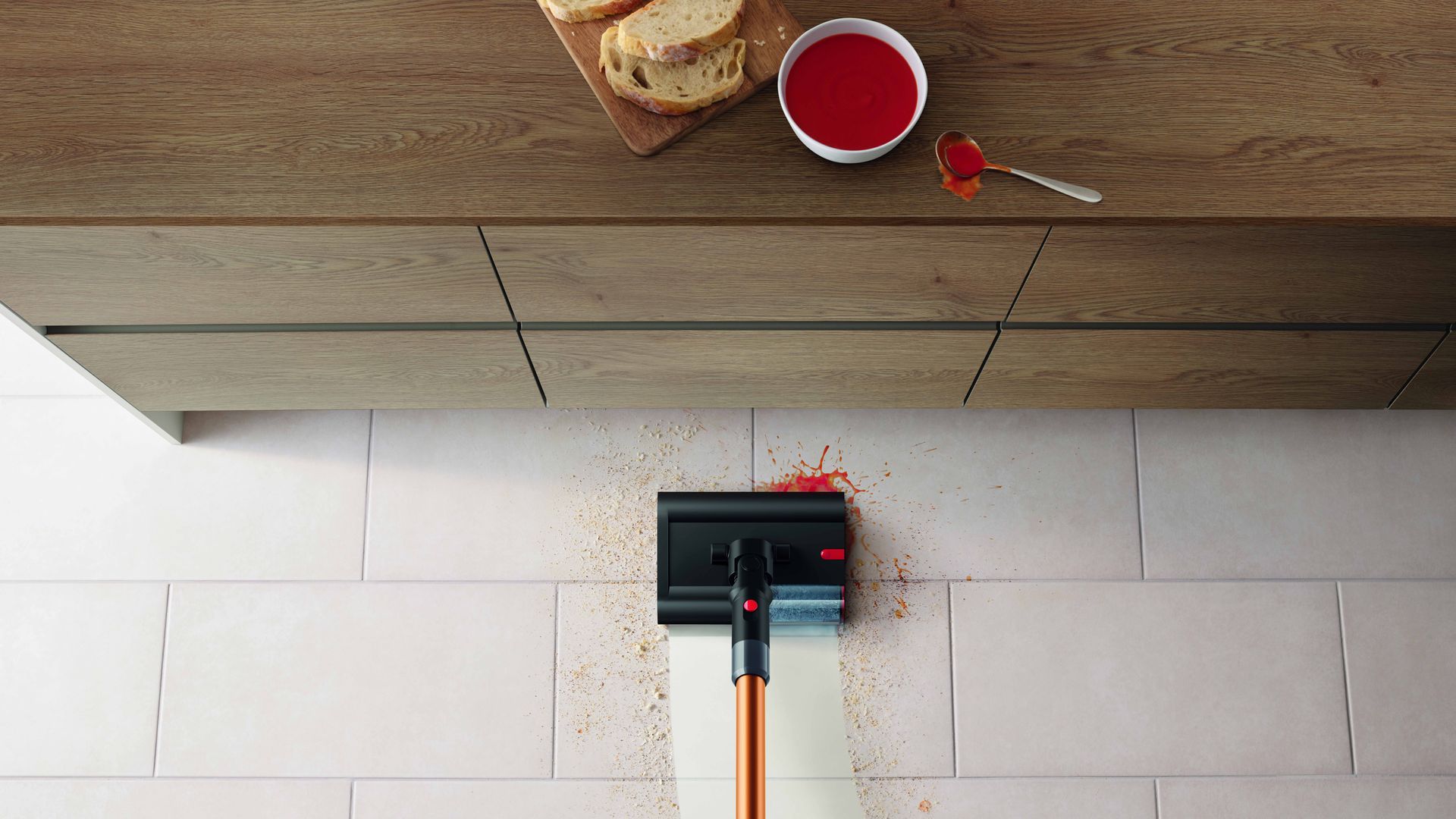 Dyson Pencilwash pasando por el suelo de la cocina recogiendo tomate del suelo.