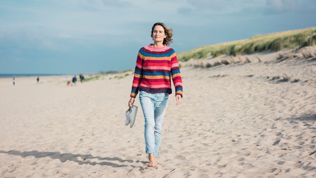mujer madura caminando sobre la arena de la playa