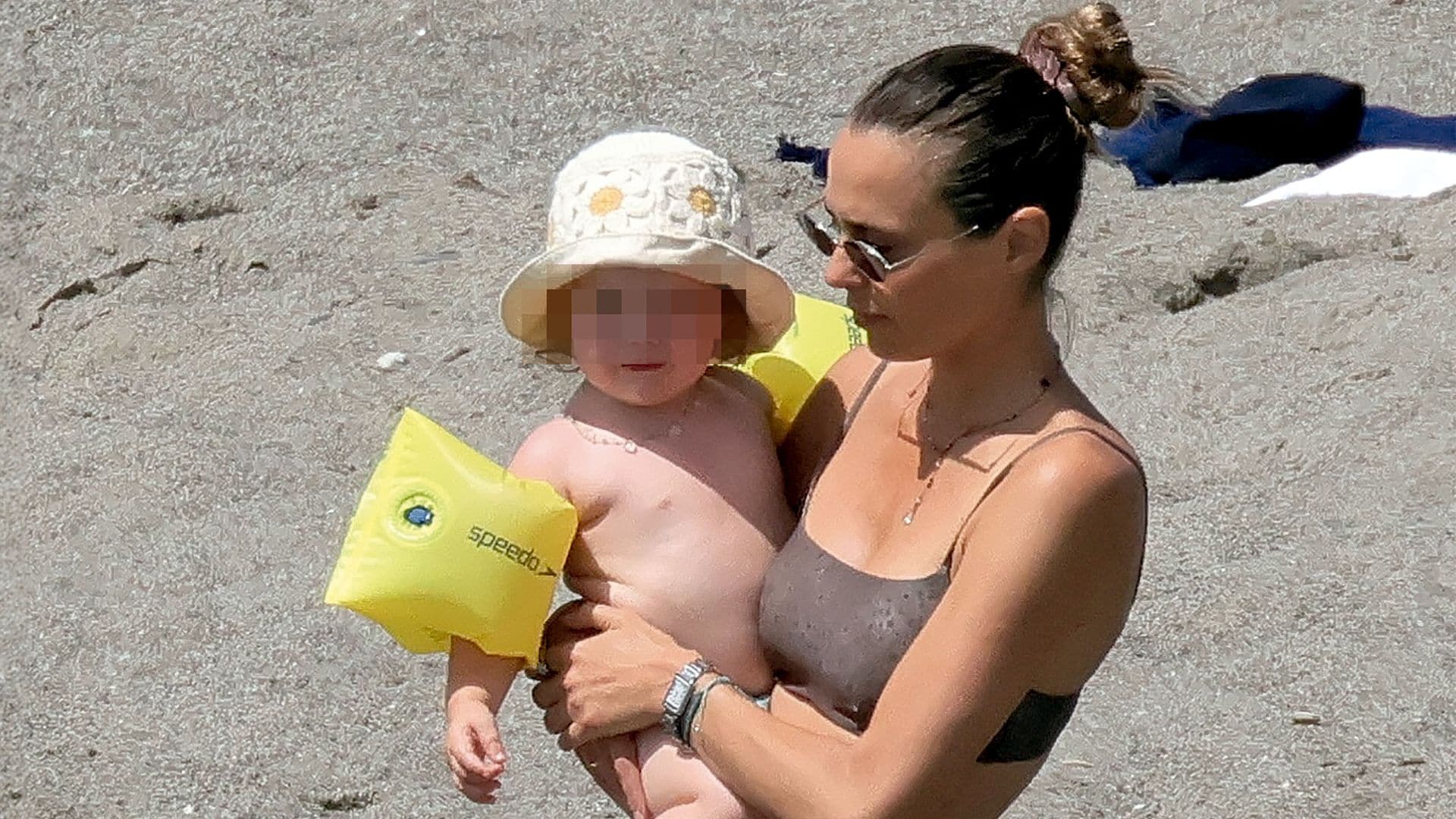 Claudia, en plena forma en bikini, lleva en brazos a la pequeña de sus hijas, Violeta