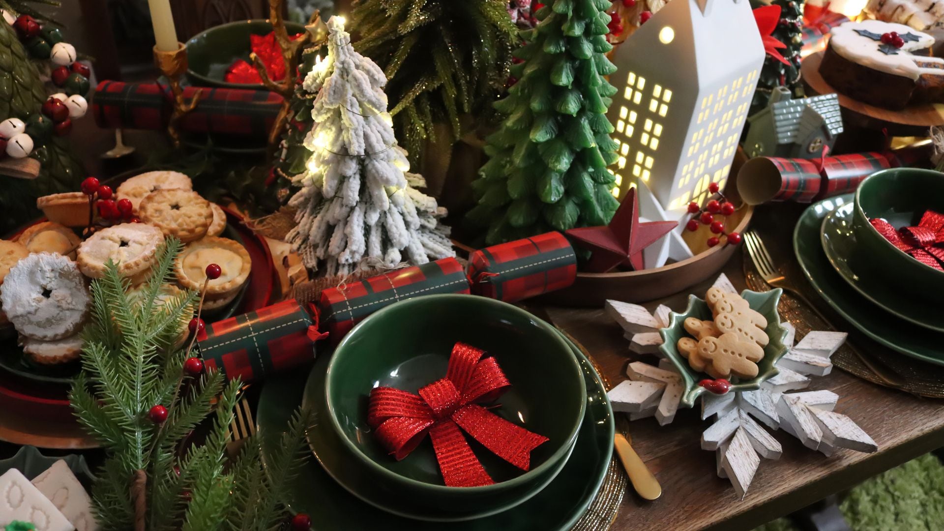 Mesa de Navidad en rojos y verdes, con decoración blanca. Repleta de galletas, dulces y crackers.