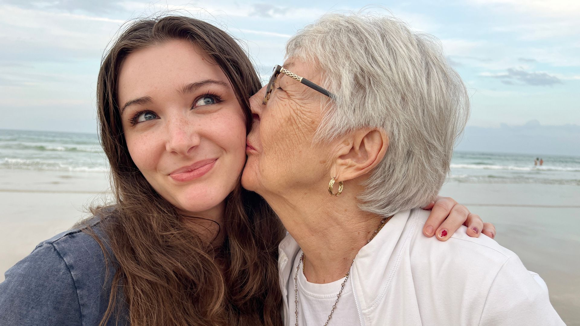 abuela dando un beso a su nieta en la playa