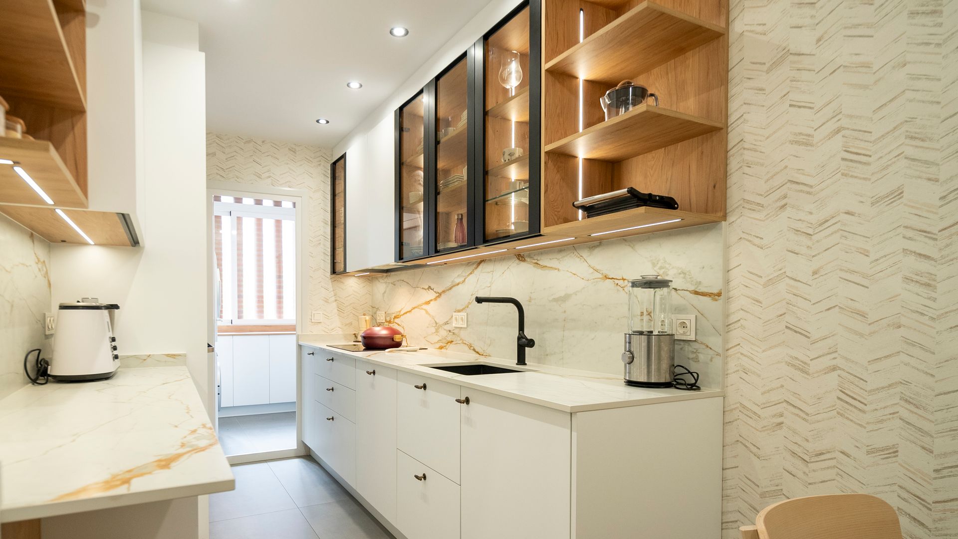 Cocina blanca abierta con muebles superiores vitrina de madera, pequeños electrodomésticos