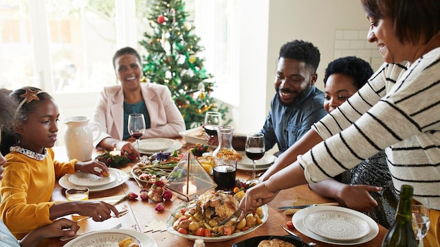 woman cutting meat for family and friends on dining table at home during christmas festival