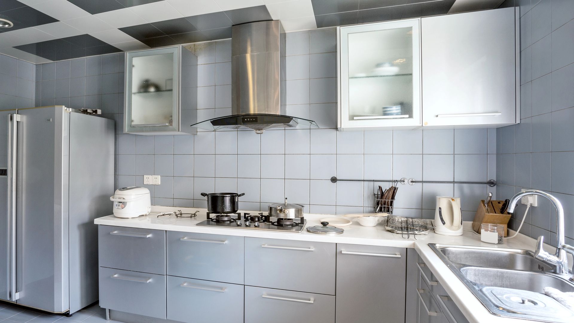 Cocina gris con azulejos grises. muebles de acero inoxidable, vitrina en la parte superior 