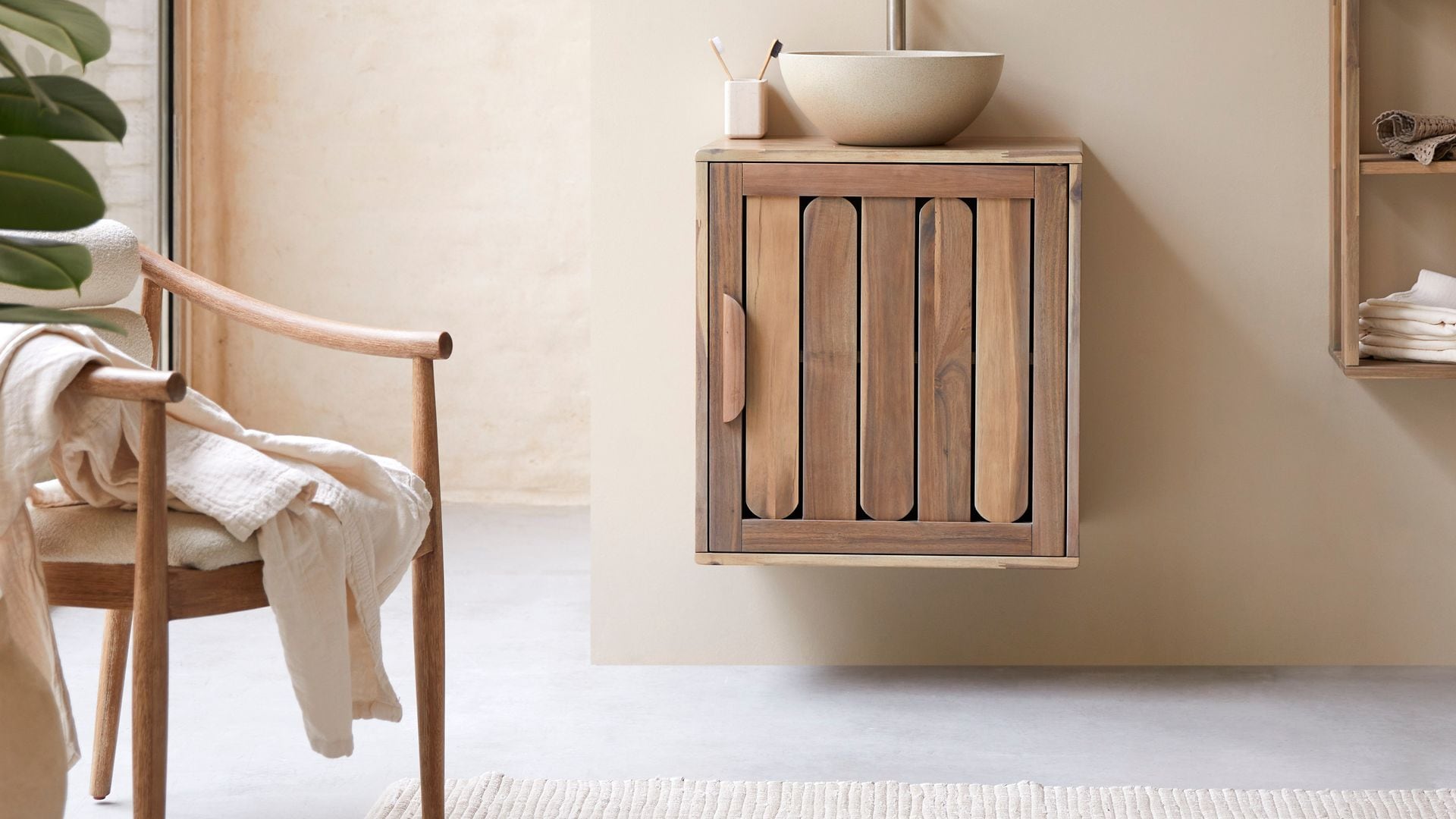 Baño con mueble bajolavabo de madera, espejo, silla de madera y lavabo redondo
