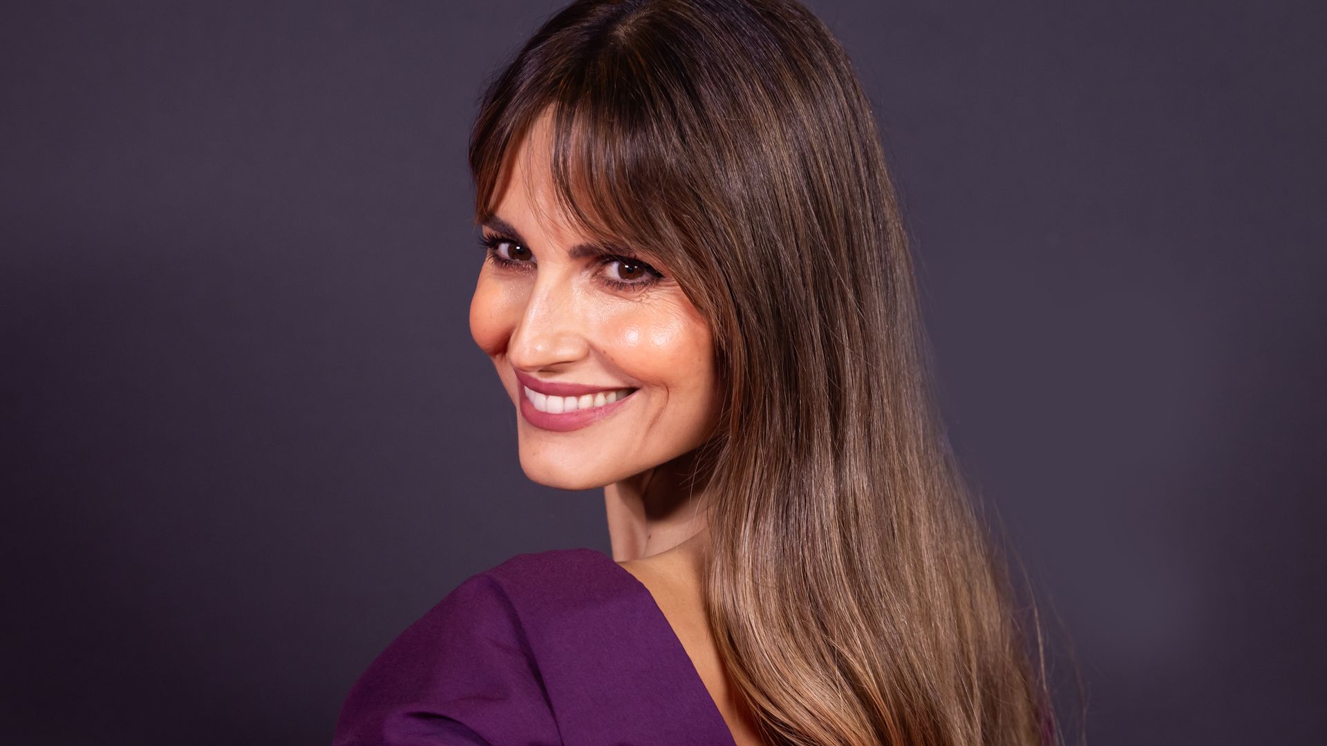 Ariadne Artiles con estilismo morado y fondo negro en una fiesta en Madrid