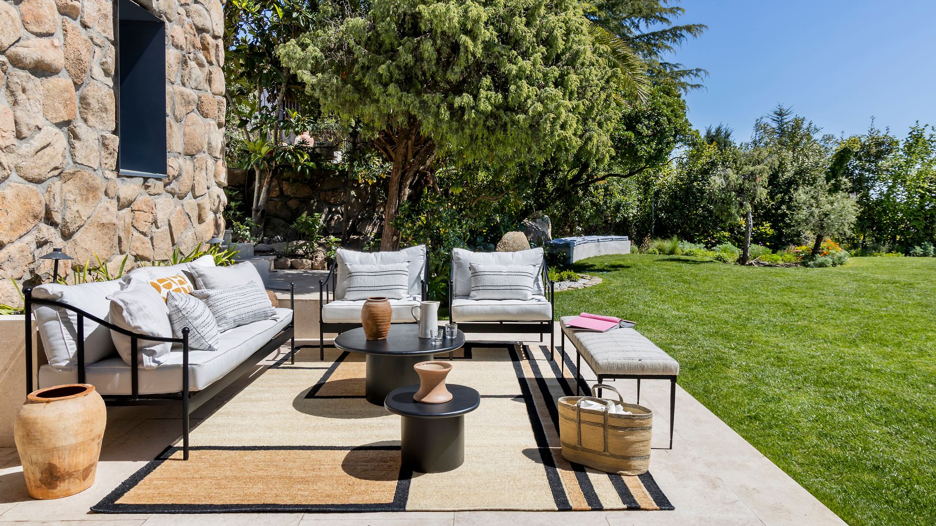 Casa con jardín con fachada de piedra, césped y salón exterior 
