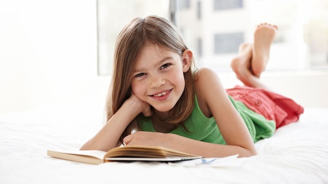 Niña lee un libro en la cama