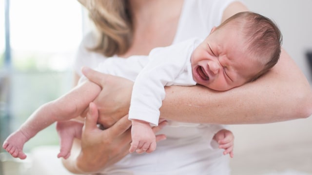 Madre intenta calmar a su bebé recién nacido, que está llorando