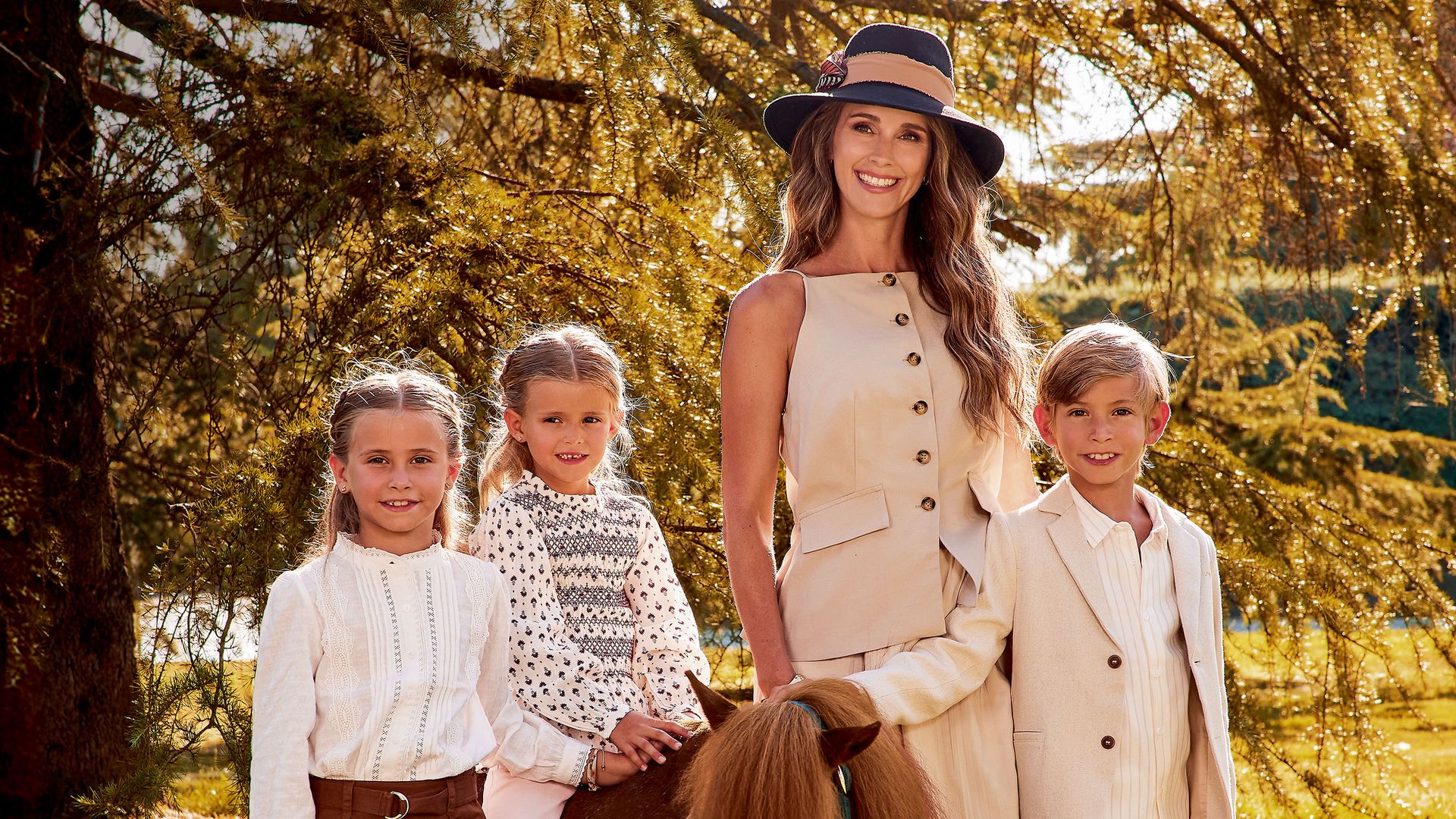 "Markuss se parece muchísimo a Carlos. Yo creo que las niñas se parecen un poco a mí, pero siempre digo que son una versión mejorada cien por cien", nos dice Astrid, junto a estas líneas, con vestido de Zara, botas de Pedro del Hierro, joyas de Aristocrazy y sombrero de Mimoki. El "blazer" de Markuss es de Nanos y los mocasines, de Coconut El Corte Inglés; los zapatos de Liene son de Birkenstock, y los de Álisse, de Coconut El Corte Inglés