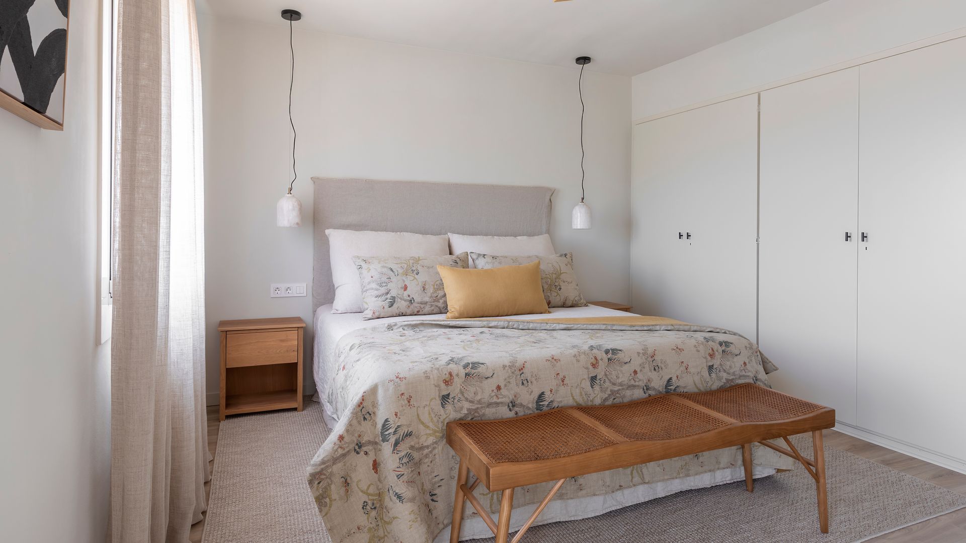 Dormitorio con ventilador en el techo, armarios blancos, banqueta a los pies de la cama, lámparas de techo colgantes a ambos lados de la cama