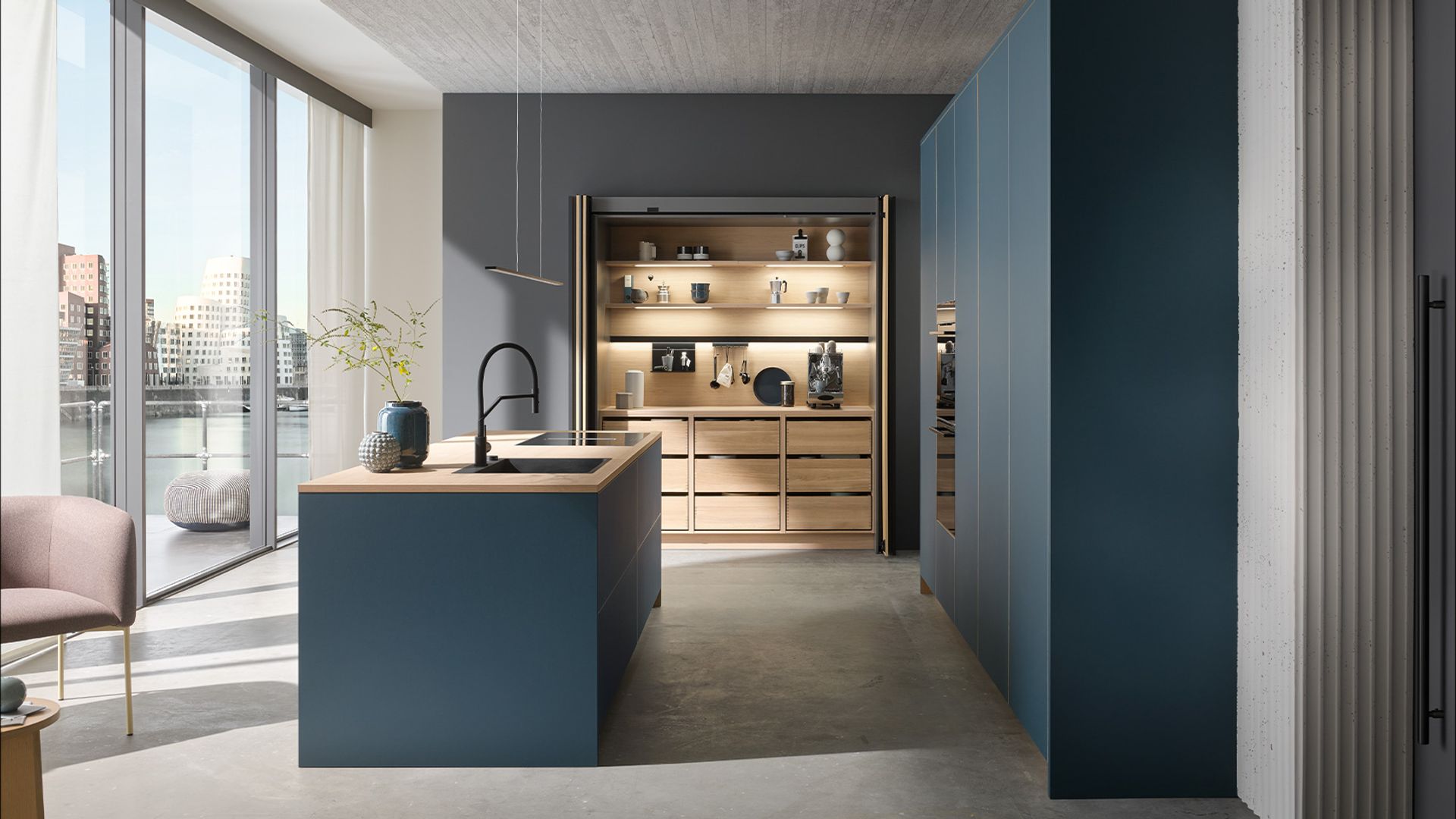 Cocina con muebles en azul petróleo, isla central, mueble despensa con puertas plegables correderas, luz interior, electrodomésticos integrados