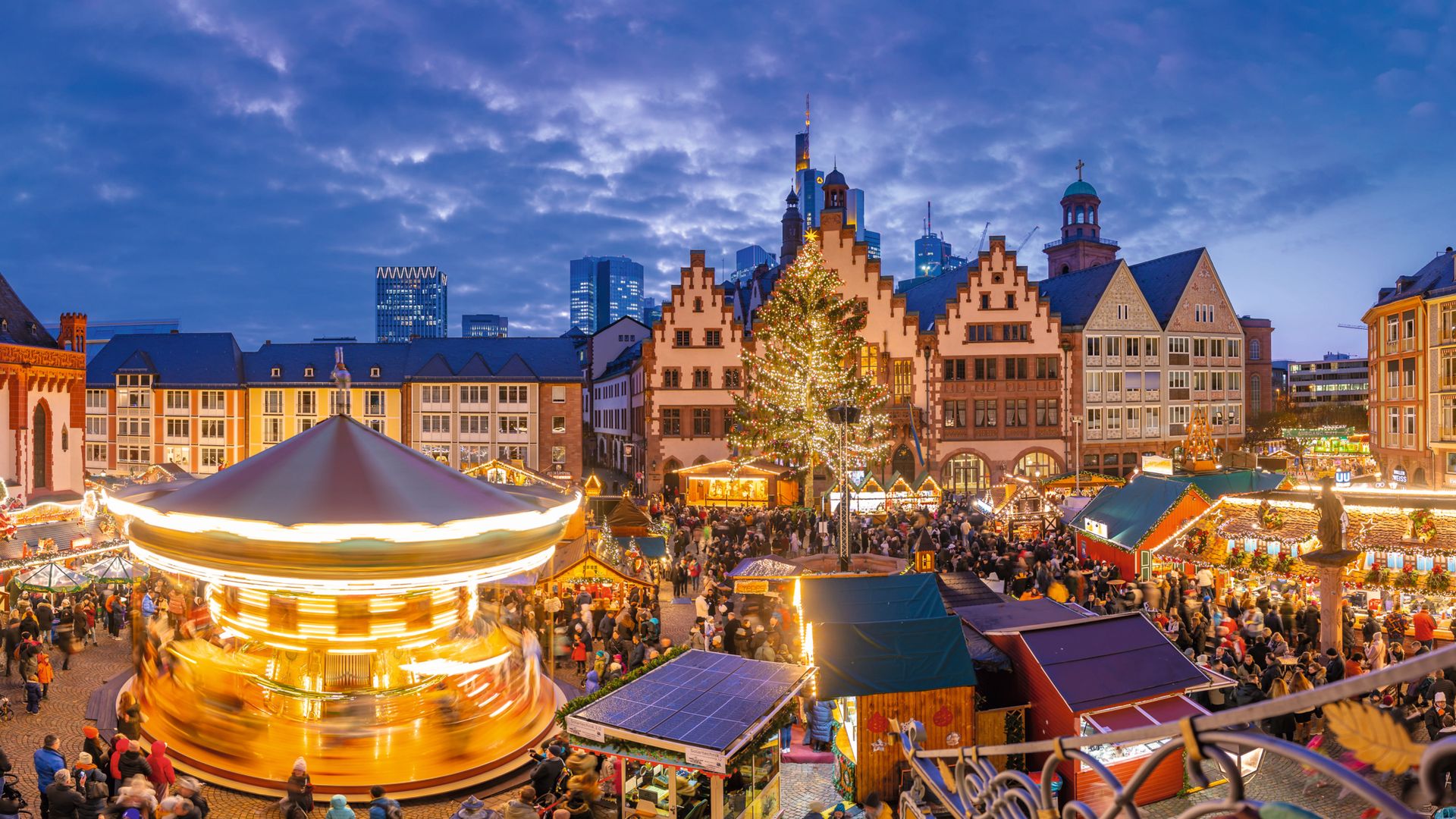 Plaza concurrida con puestos navideños, no se detectan celebridades.