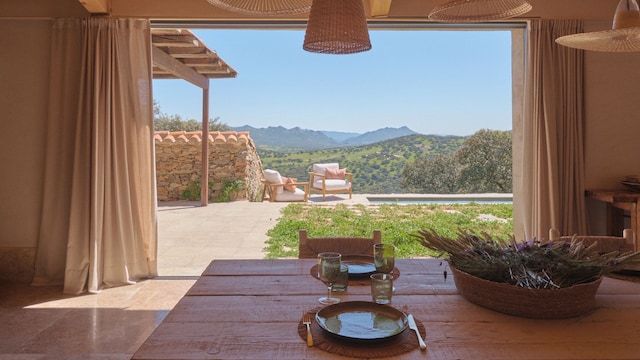 Comedor abierto a la piscina con mesa de madera, cesto con lavanda, platos y lámparas de fibras vegetales