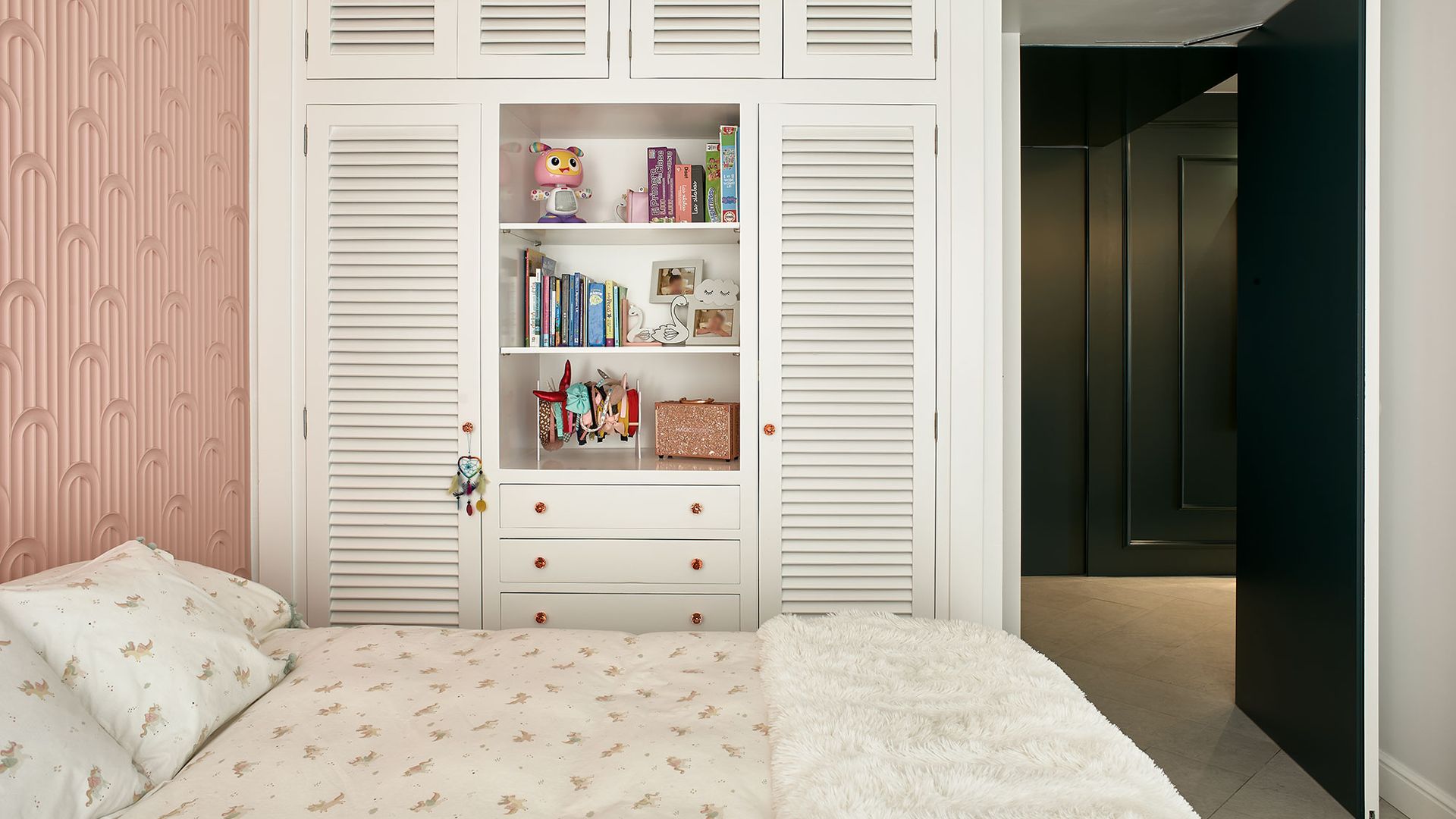 Habitación infantil con armario a medida de lamas blancas, estantería central  y cajonera 