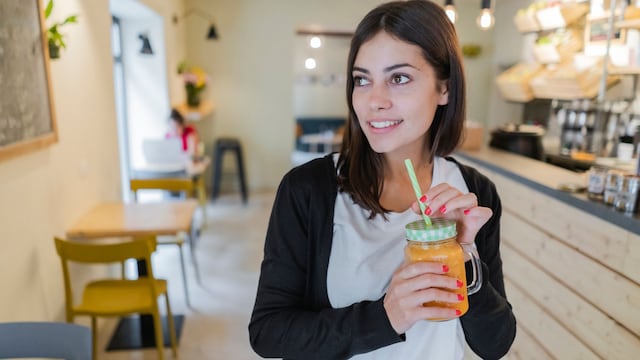 Mujer joven y guapa tomando un zumo de naranja