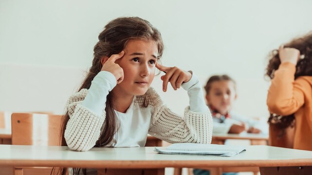 Niña en clase con gesto de agobio