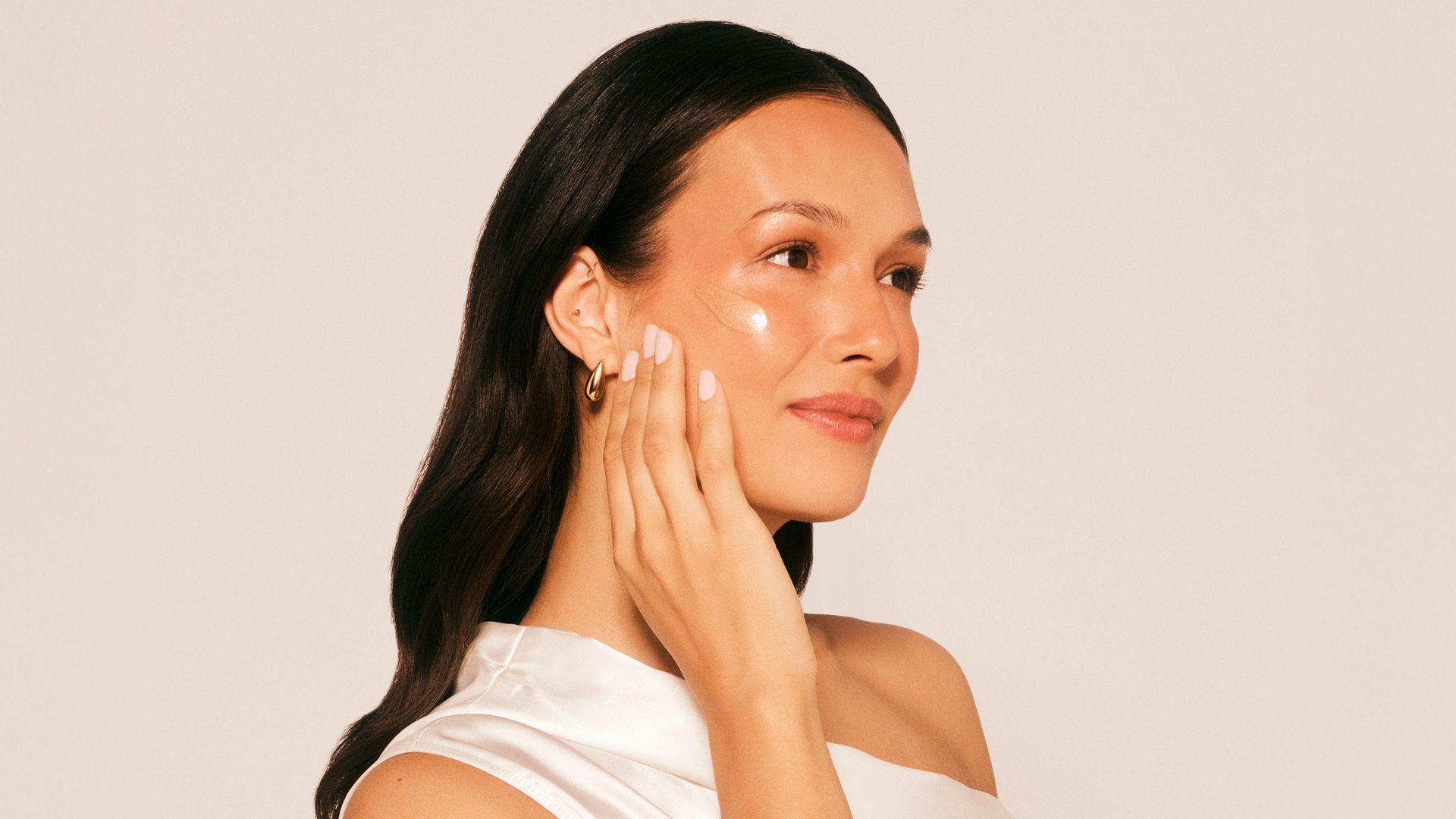 Rostro de mujer morena aplicándose DD Cream de Atashi en la mejilla