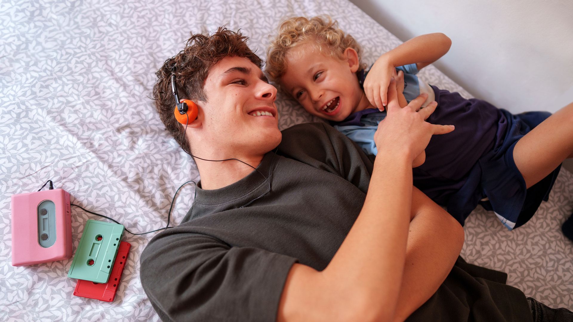 hermano mayor y su hermano pequeño, jugando juntos tumbados en la cama