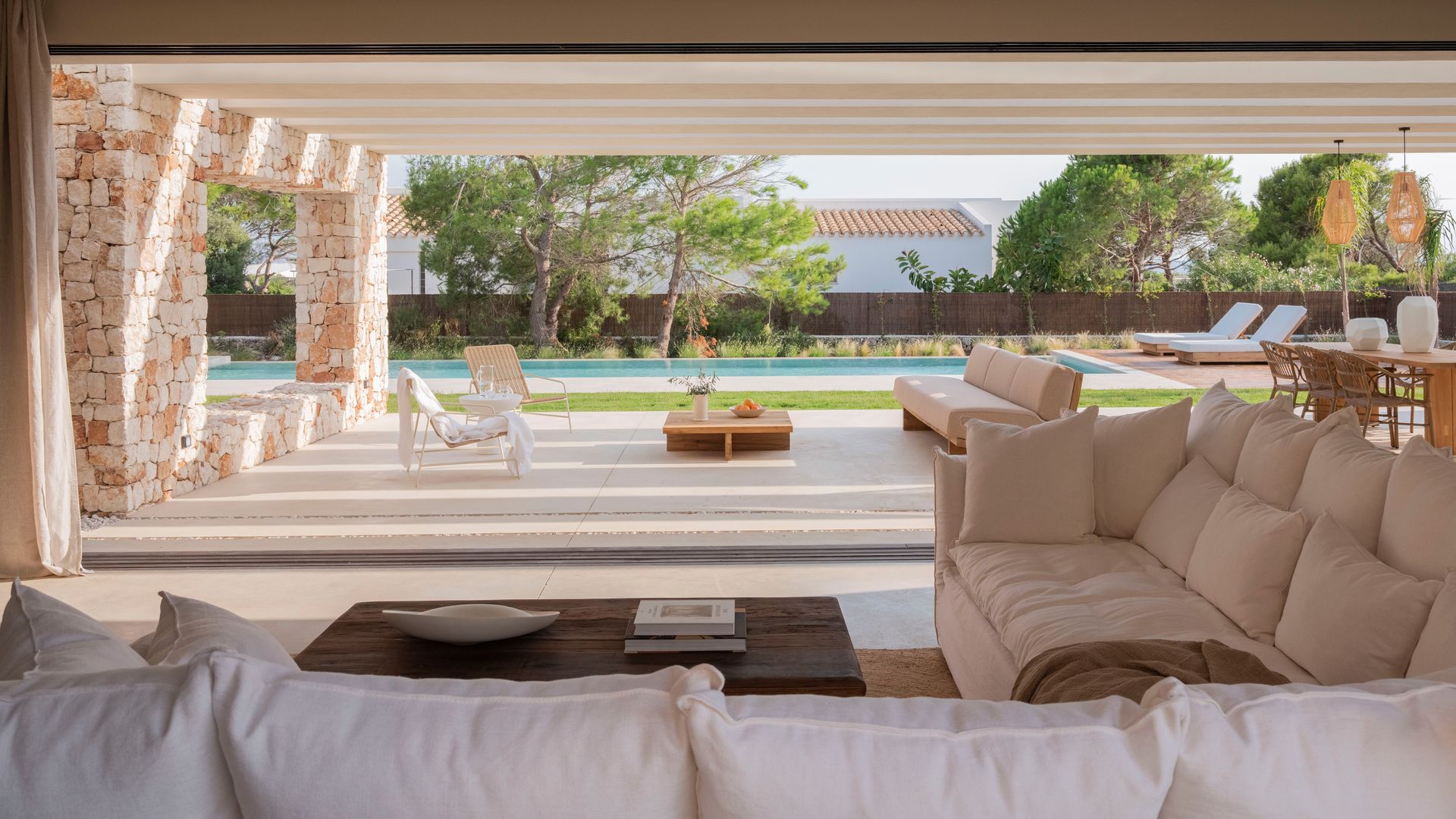 Salón de estilo mediterráneo con sofá beige y abierto al jardín  