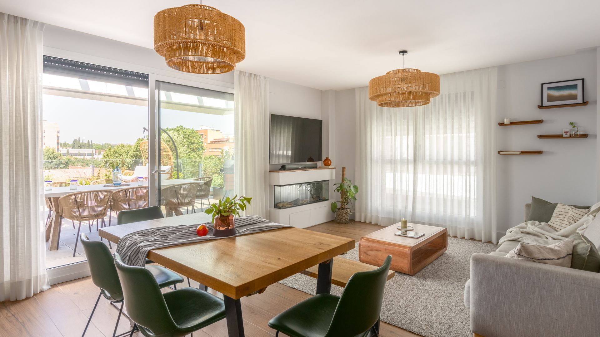Salón comedor con chimenea, televisión colgada en la pared, lámparas de techo de fibras vegetales, salida a la terraza, puerta corredera, mesa de centro de madera, mesa de comedor de madera