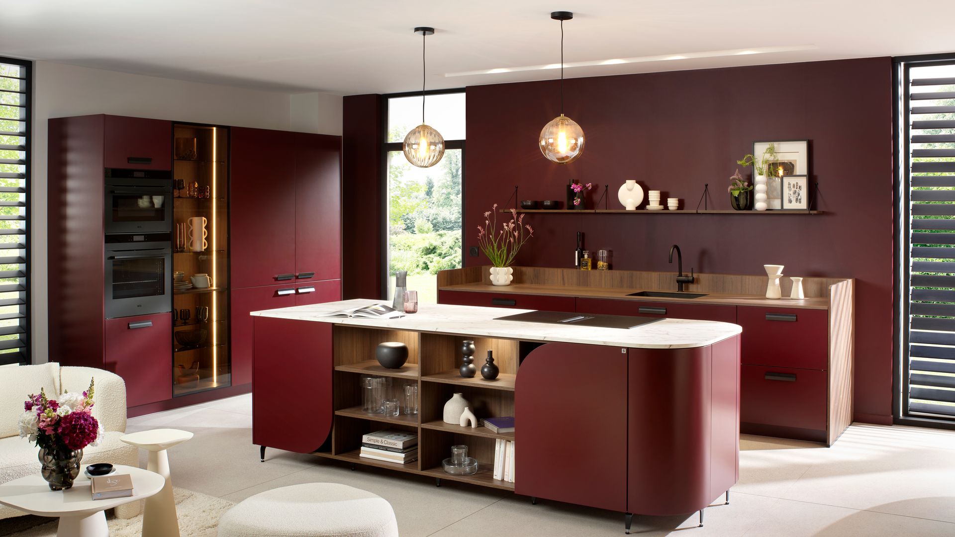 Cocina abierta con paredes y muebles en color burdeos, lámparas de techo 