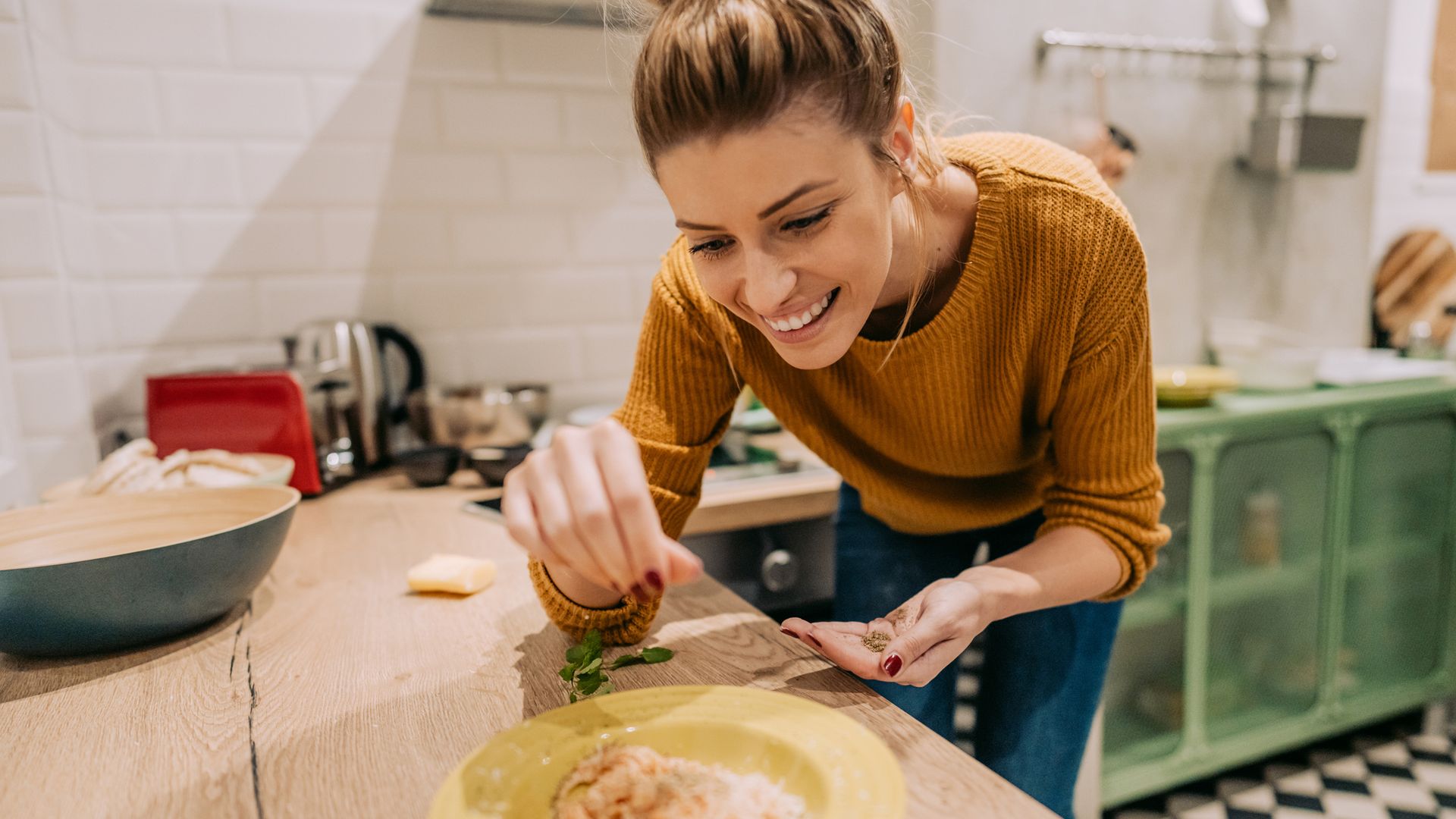 Mujer cocinando pasta y añadiendo especias