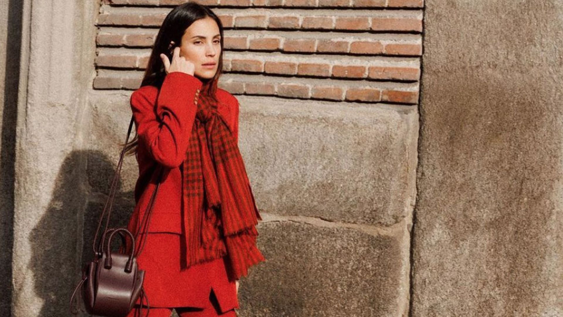 El look navideño de Sassa de Osma con traje rojo, bufanda estampada y bolso de Ubrique