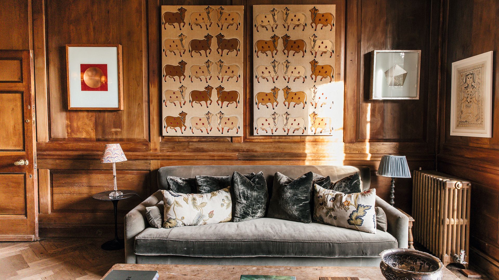 Sala de estar con sofá gris, almohadas, y arte en las paredes.