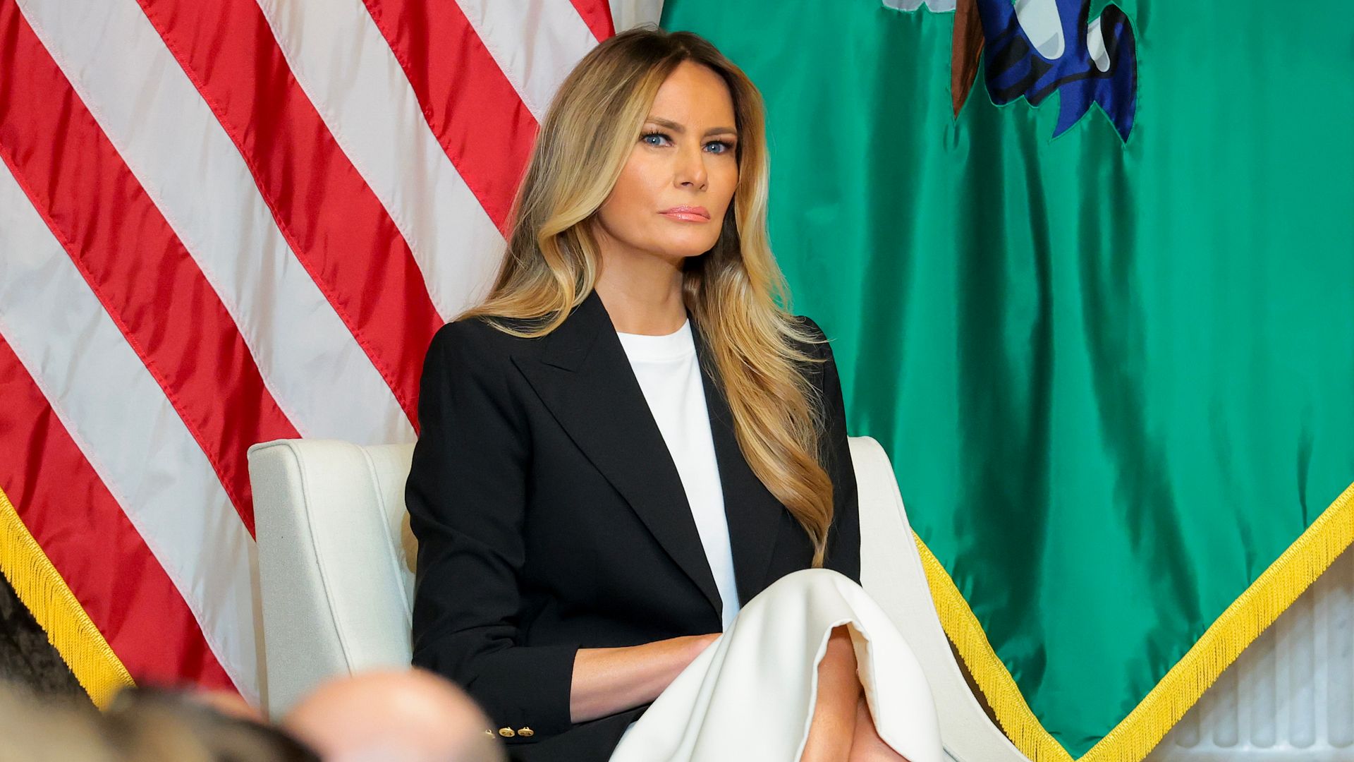 Melania Trump con vestido blanco satinado y americana negra
