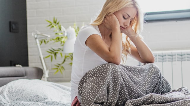 mujer preocupada sentada en la cama