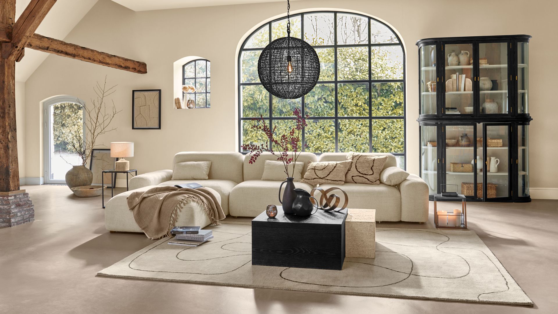 Salón con sofá blanco, mesa de centro de madera negra y bloque de m´ñarmol blanco, alfombra, lámpara de techo negra, vitrina negra 