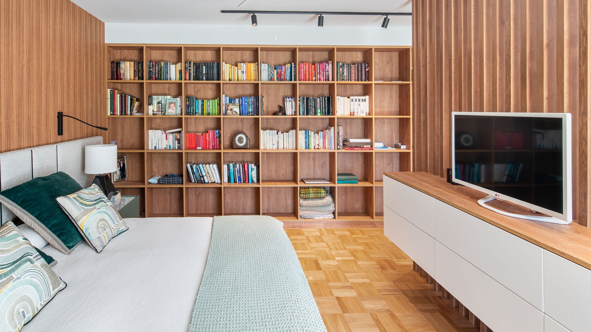 Dormitorio con librería a medida de madera, mueble de televisión, pared del cabecero de madera