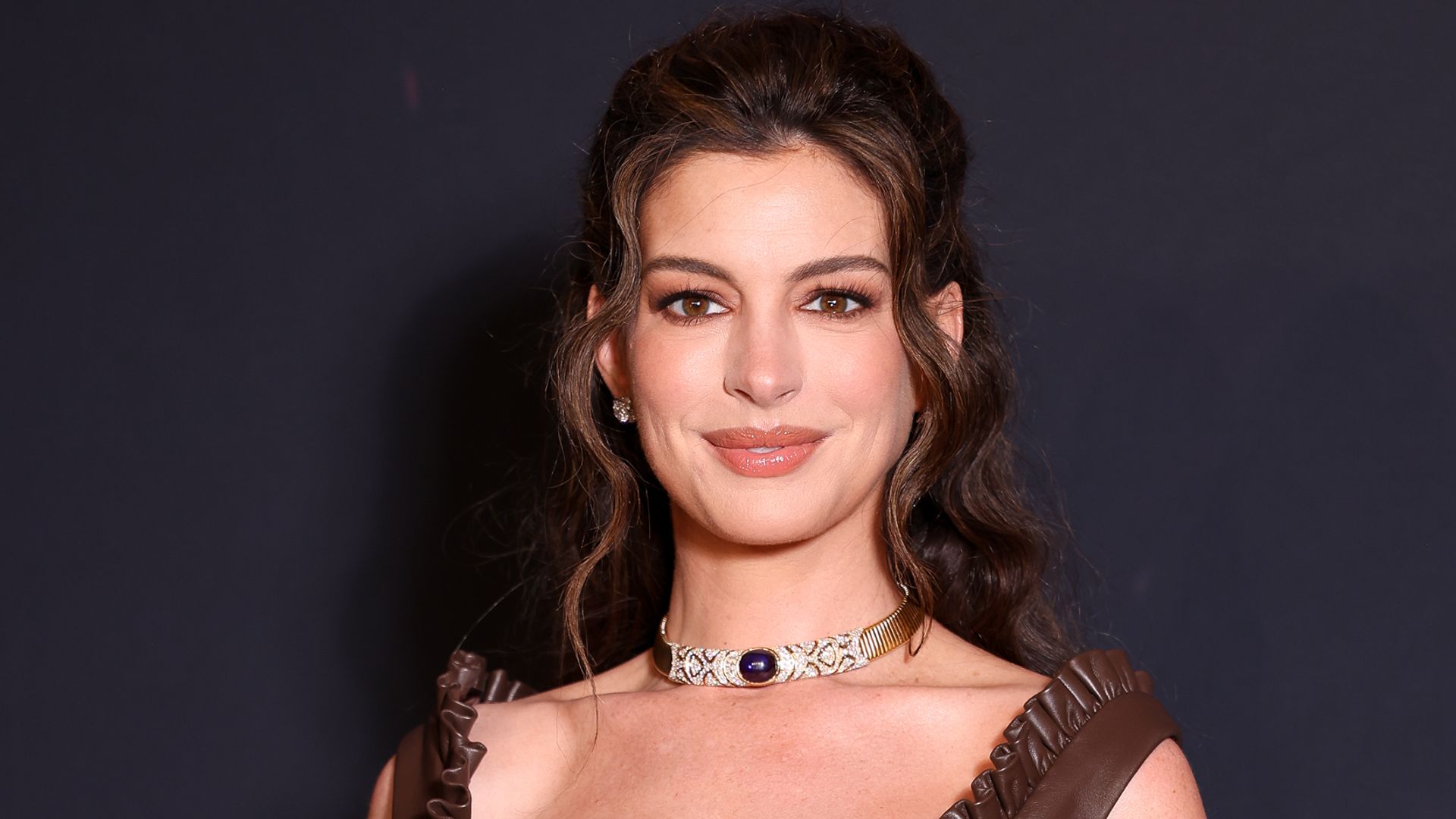 Anne Hathaway en el estreno de La odisea en París con vestido marrón y pelo en un semirrecogido