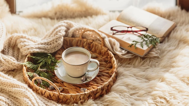 Decoración de invierno con mantas, una taza de café y un libro