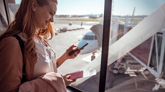 young woman using a phone while waiting to board the airplane