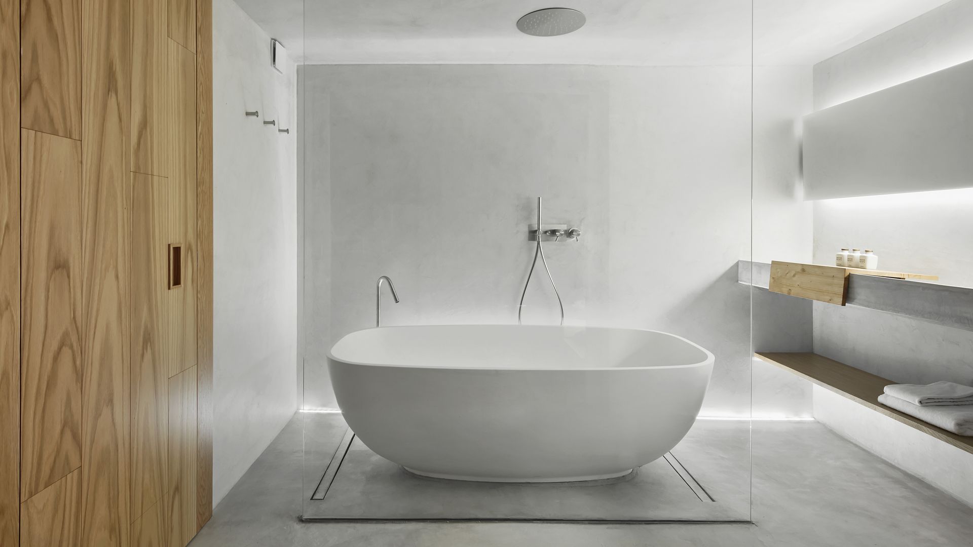 Baño con bañera exenta, suelo de microcemento, puerta corredera de madera, tabique de cristal