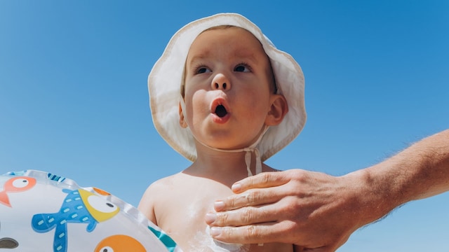 Padre poniendo crema solar a su hijo