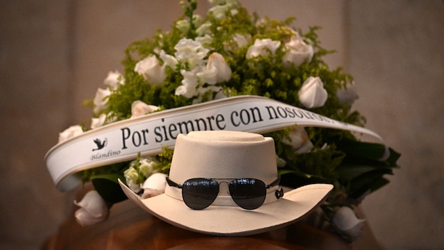 Un sombrero y unos lentes oscuros fueron colocados sobre el féretro de Rubby Pérez junto a un arreglo floral con la leyenda "Siempre con nosotros".