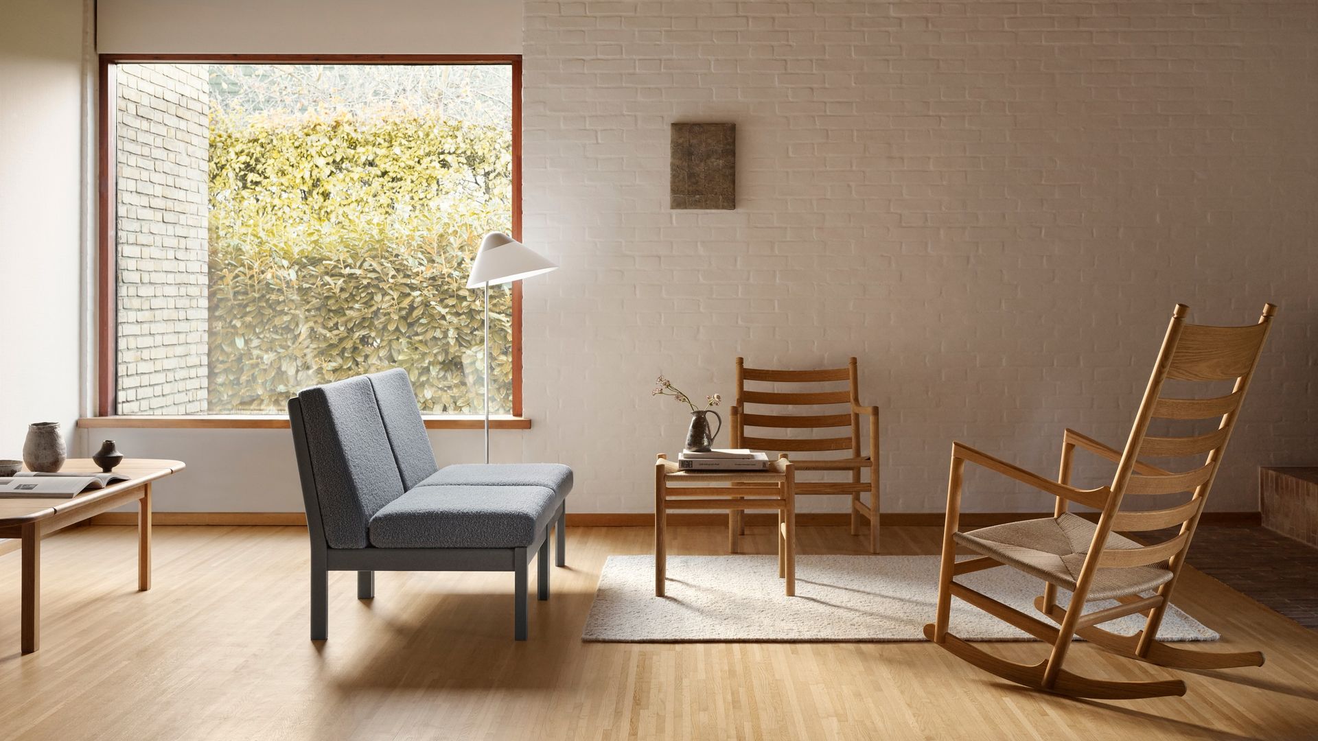 Salón de estilo nórdico con sofá gris, alfombra, mecedora de madera, lámpara de pie, techo de madera