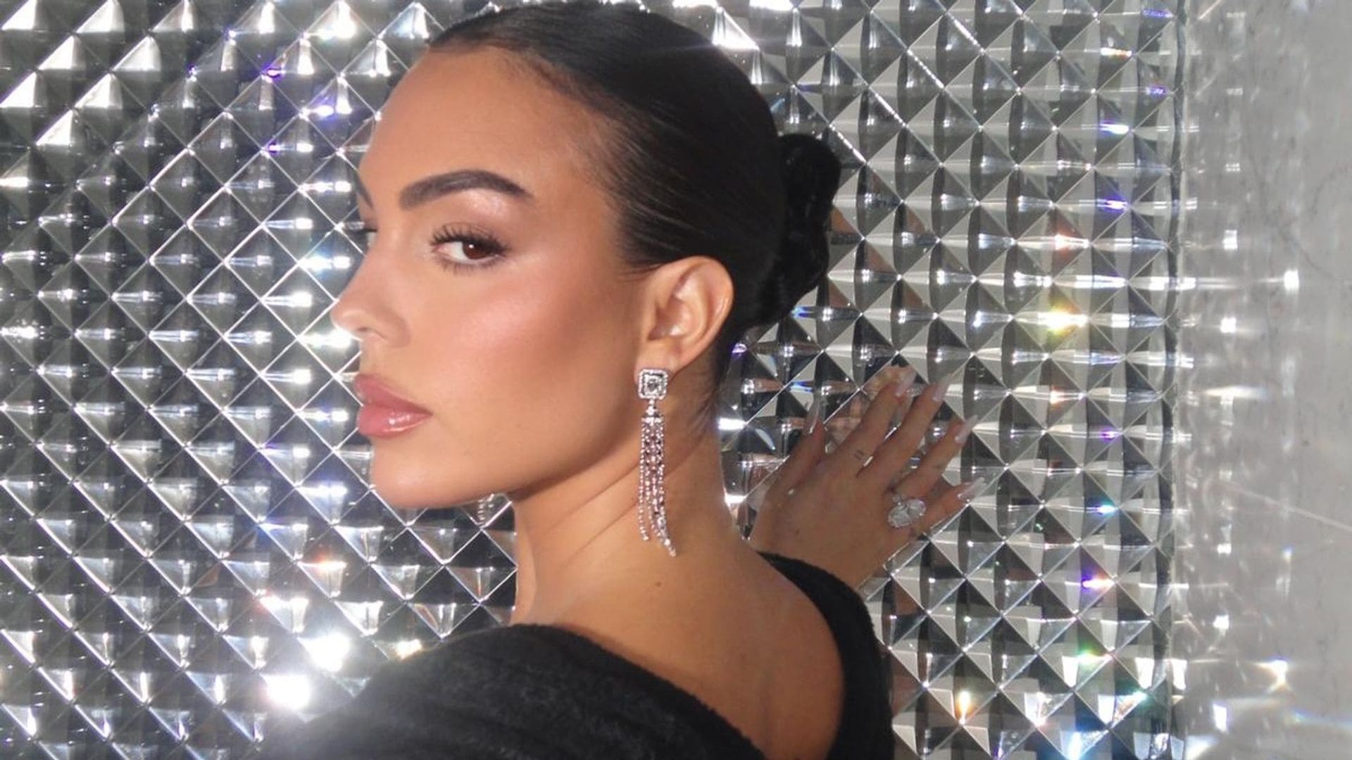 Georgina Rodríguez con vestido negro, pendientes de diamantes sobre pared metalizada