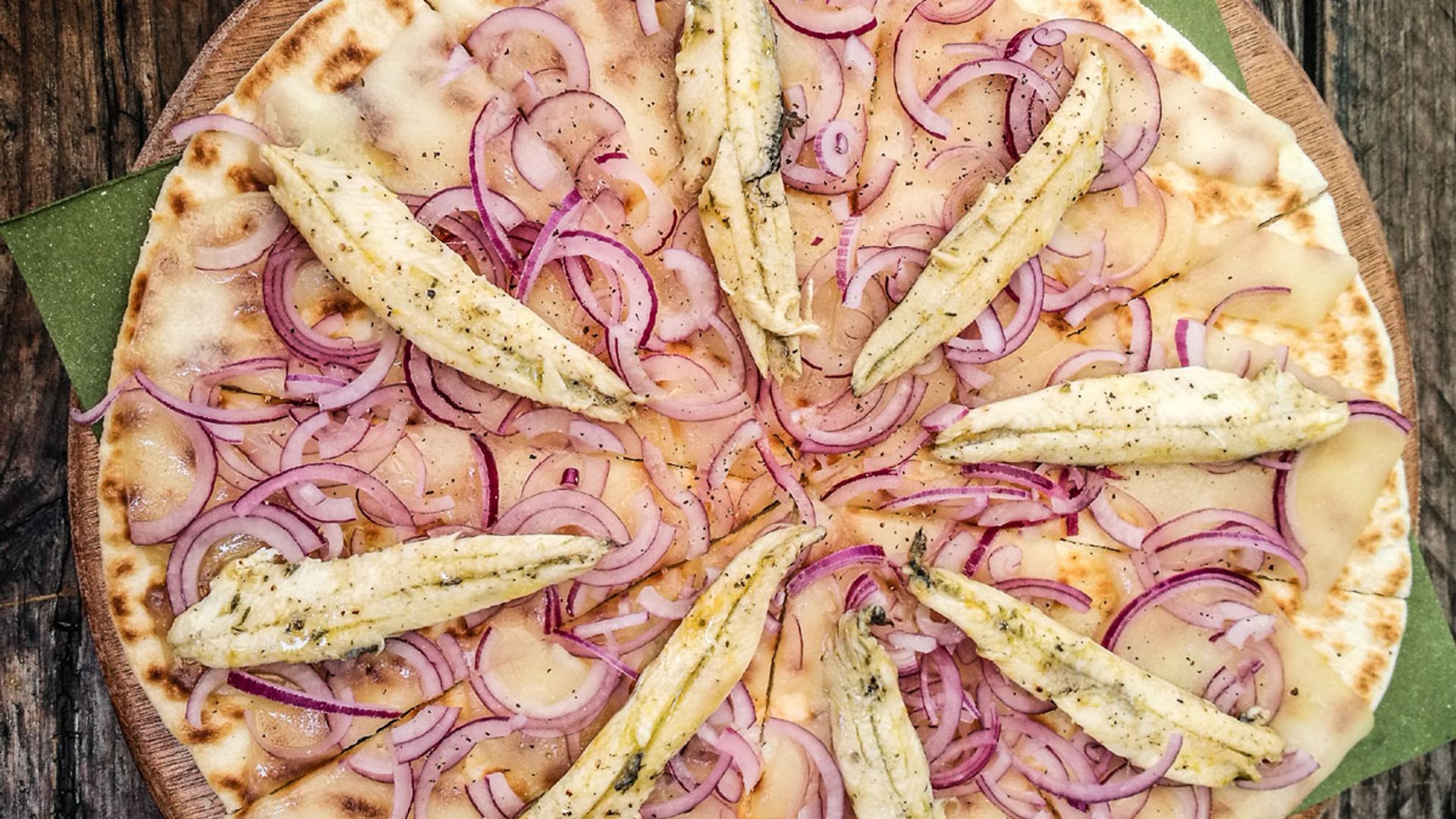 Pizza con base de piadina, boquerones y cebolla morada